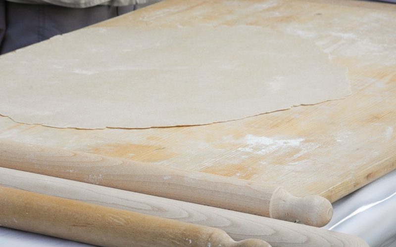 Su di una spianatoia in legno è posta ad asciugare la sfoglia dei tajulì pilusi. Nell'aria il profumo delle farine antiche impiegate.