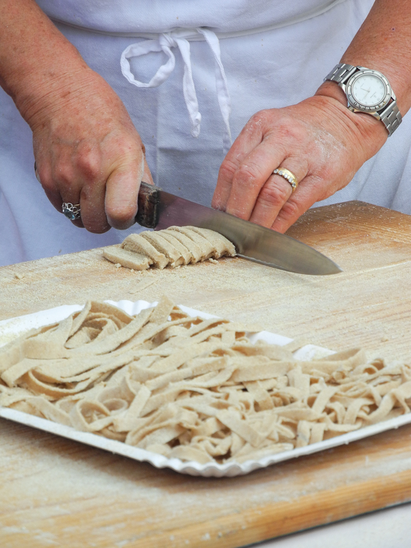 Abili mani di vergara tagliano, grazie all'ausilio di un affilato coltello, sottili tagliolini.